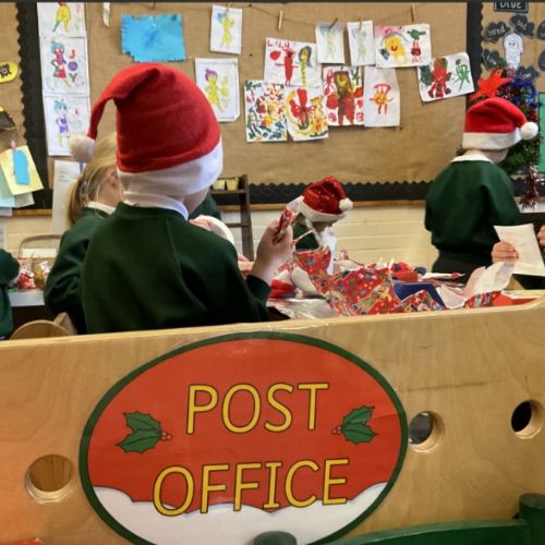 Apple Class fully emersed in the Christmas post office writing area-- wrapping toys and writing Christmas cards to post.